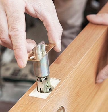 Close-up carpenter hands door lock installation.